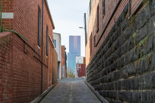 Low angled view of stonework in a city laneway with a skyscaper in the distance
