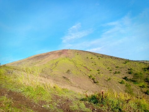 Grassy volcanic hill under blue sky in Garut West Java