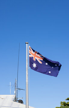 Australian national flag flying from a flagpole against a clear bright blue sky