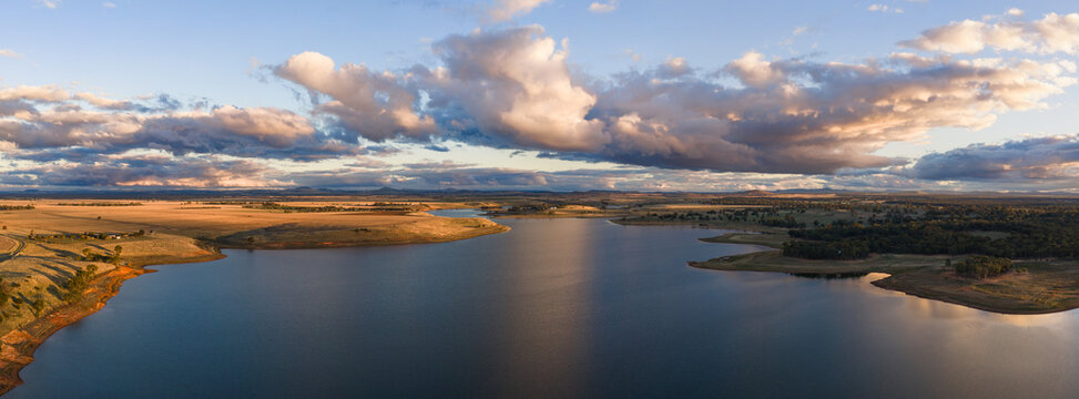 Aerial panorama view of colourful clouds reflected on an inland lake at sunset