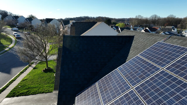 Aerial view of solar panels installed on a residential roof in a suburban neighborhood with green lawns and trees in Rohrerstown, Pennsylvania, United States.