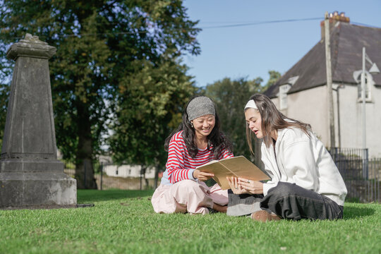 Young women studying book together in a cemetery