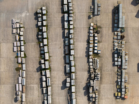 Aerial view of stacked concrete blocks and construction materials in rows in an industrial yard with long shadows in Lisburn, Northern Ireland, United Kingdom.