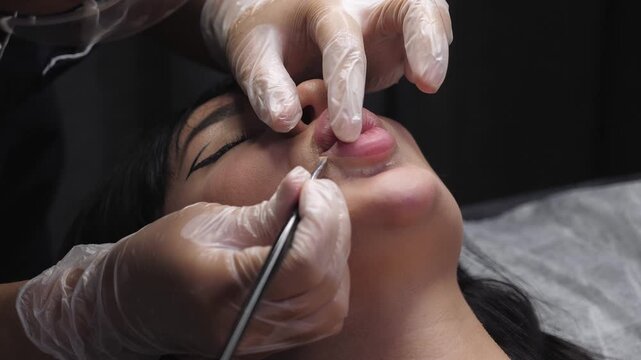 In detail, a beauty expert employs a brush to define the shape of a woman's lips prior to the tattooing process. Permanent lip makeup in a contemporary beauty establishment.