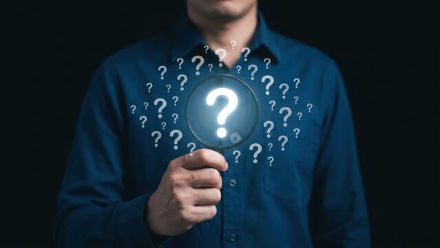 Man holding a magnifying glass looking for answers with many floating question marks