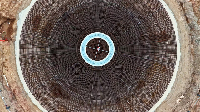 Aerial view of a circular wind turbine foundation featuring intricate steel rebar reinforcement patterns set within a construction site in Latvija.