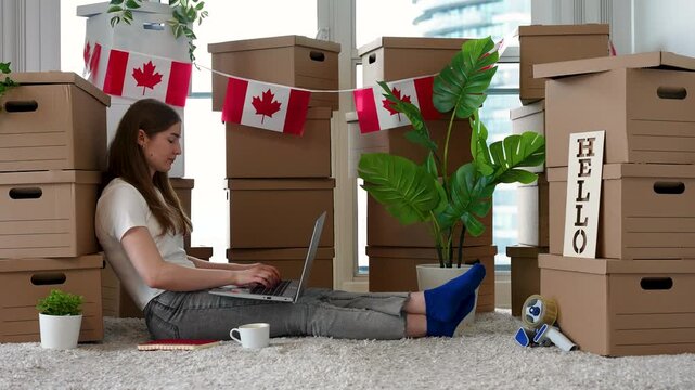 Young Woman Using Laptop During Move to New Home in Canada