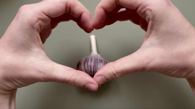 Hands Forming a Heart Shape Around a Garlic Bulb