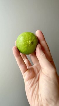 Hand Holding a Whole Green Lime Vertical Video