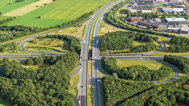 Aerial view of cloverleaf Drachten interchange surrounded by green fields and trees in Drachten, Friesland, Netherlands.