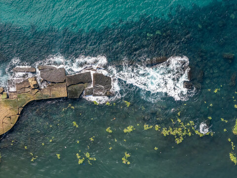 Aerial view of the stone breakwater at the mouth of the Rio Ozama with waves crashing against the rocks and clear water in Santo Domingo, Santo Domingo, Dominican Republic.