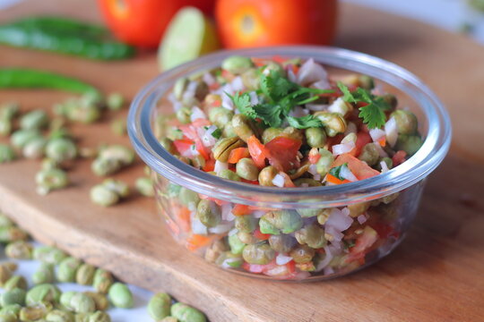 Roasted edamame bean salad with tomato, onion, carrot and fresh coriander in a glass bowl