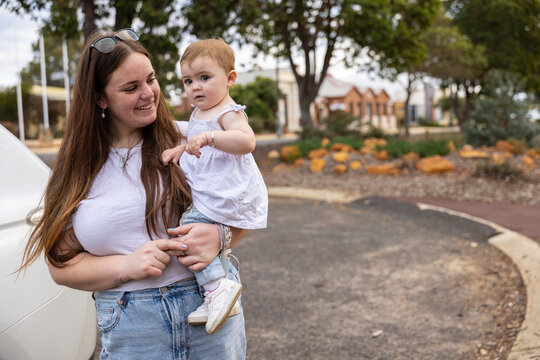 Young mother carrying toddler outdoors in Australian suburban neighbourhood