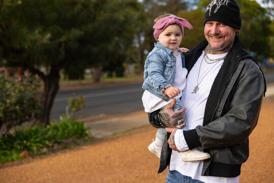 Smiling father holding toddler daughter outdoors in Australian neighbourhood