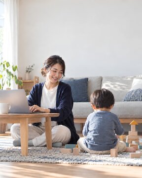 Japanese parent working on laptop at home while child plays nearby