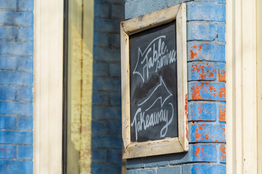 Close up of a chalk board sign on the side of a colourful brick wall