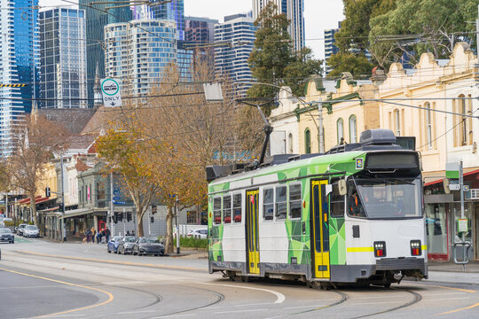Commuter tram on a street of historic buildings in front of a city skyline