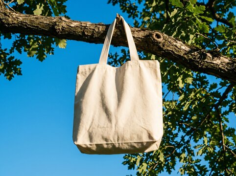 Reusable tote bag hanging on tree branch outdoors