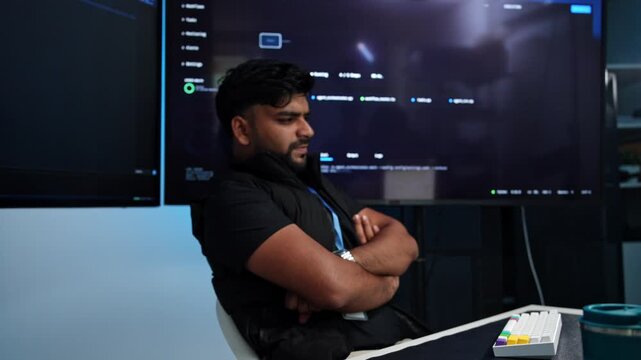 Bearded coder intensely focused on screens in dim tech office