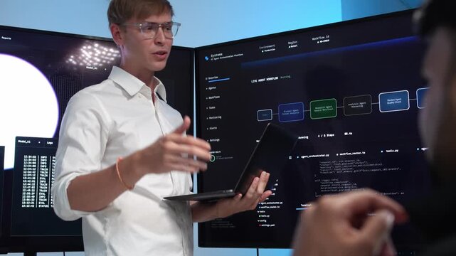 Engineer shows AI workflow on screens with colleague