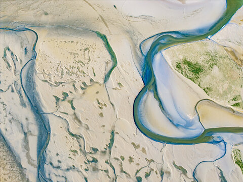 Aerial view of the intricate tidal channels and sandbanks of the Baie de Somme with winding water paths and textured sediment patterns in Saint-Valery-sur-Somme, Hauts-de-France, France.