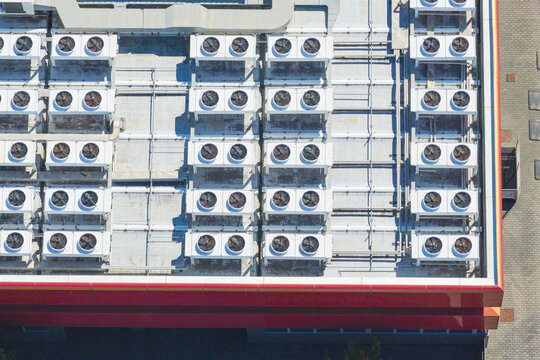 Aerial view of multiple HVAC cooling units installed on a flat industrial rooftop in Arezzo, Tuscany, Italy.