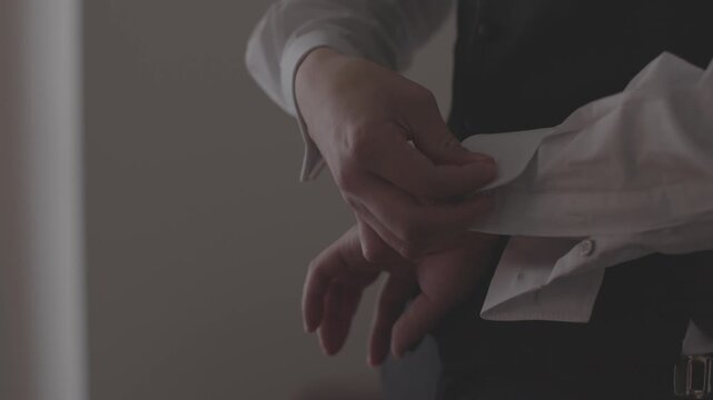 結婚式の身支度でタキシードの袖口のカフスボタンを留める新郎の手元のアップ