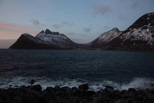 Dramatic snowy mountains over a fjord at twilight in Norway