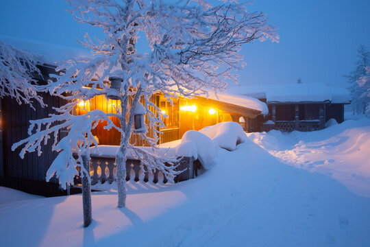 Warm lights glow from a snow covered winter cabin