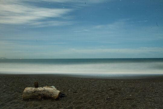Calm ocean beach at night with driftwood on sand