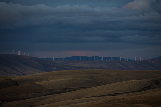 Wind turbines on rolling hills under a stormy sky