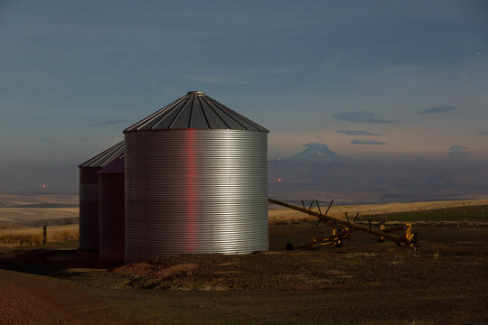 Grain silos on farmland with a mountain at twilight