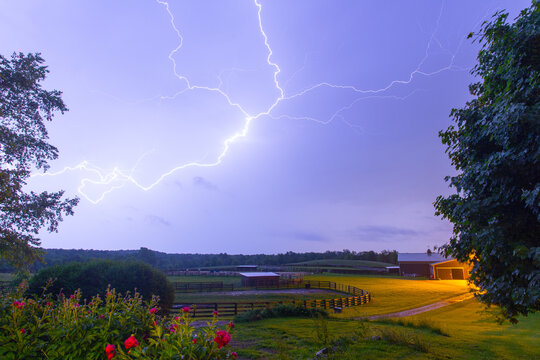 Dramatic lightning flashes over a farm at dusk