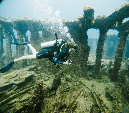 Female scuba diver explores a sunken shipwreck