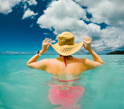 Woman holding her sun hat in tropical water