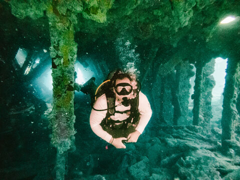 Woman scuba diving inside an eerie sunken shipwreck