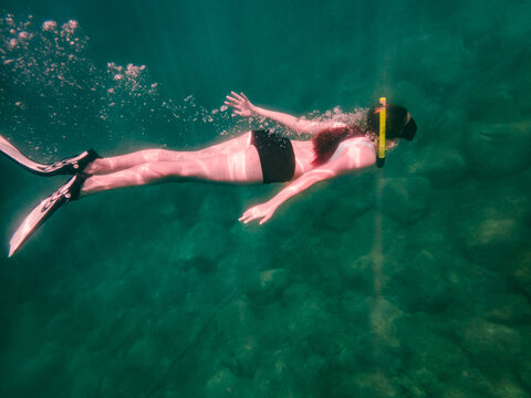 Young woman snorkeling in turquoise ocean water