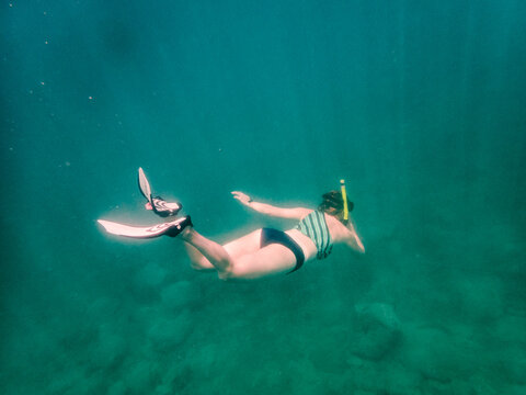 Woman with snorkel and fins swims underwater