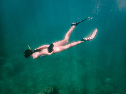 Woman free diving through clear turquoise water