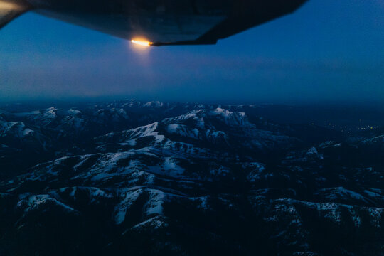 Snow covered mountain range seen from a small aircraft at dusk.