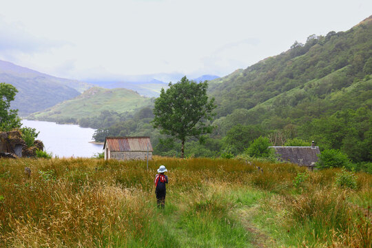 Lone girl hiker walking in a vast green mountain valley in Scotland