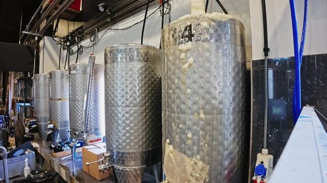 Stainless steel beer fermenter overflowing with foam