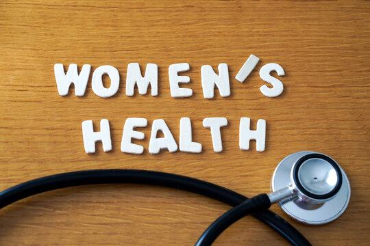 The words women's health" formed with wooden letters, accompanied by a black medical stethoscope.