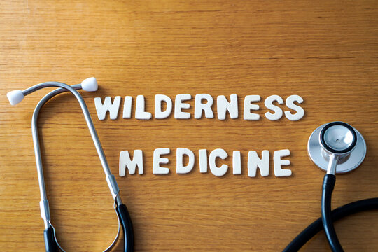 The words wilderness medicine formed with wooden letters, accompanied by a black medical stethoscope