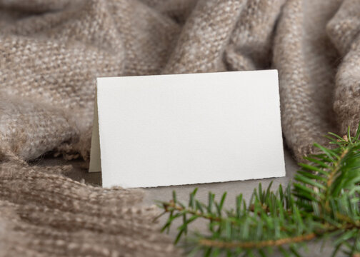 Folded horizontal card mockup near green fir branches on grey stone. Rustic holiday scene