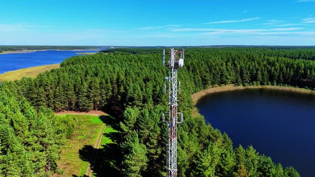 Aerial view of cellular tower surrounded by lush green forest and serene lake shoreline