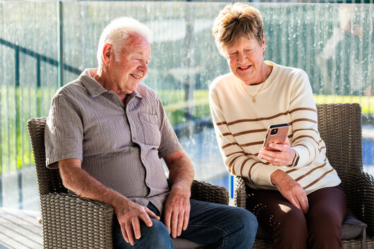 older Australian people sitting together in backyard using mobile device to connect with family