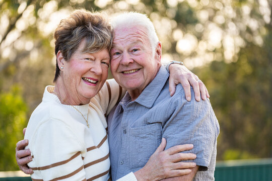 hugging senior Australian couple in their seventies together in backyard