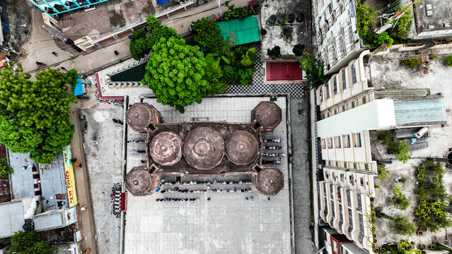 Aerial view of the historic Khan Mohammad Mridha Mosque with its distinctive domes and courtyard surrounded by urban buildings and lush trees in Dhaka, Dhaka Division, Bangladesh.