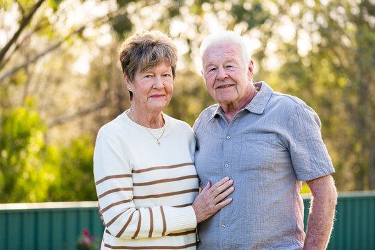 portrait of happy senior Australian couple in their seventies together in backyard